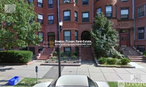 A street view of a residential area with apartment buildings and parked cars.