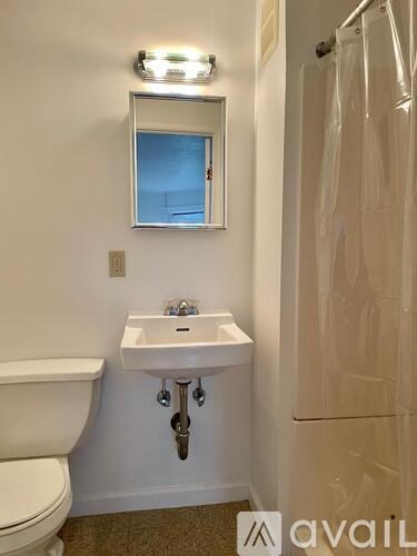 A bathroom with a sink, toilet, mirror and shower.