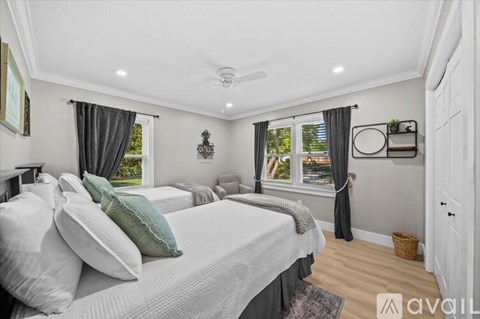 A bedroom with a large bed and a window with curtains.