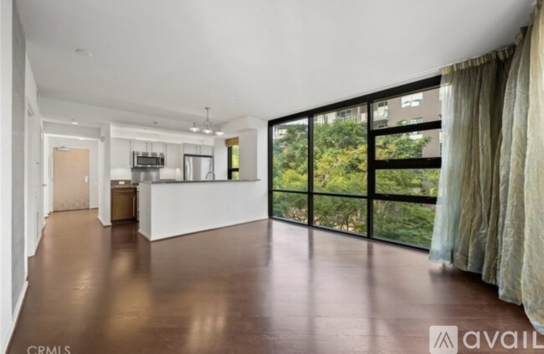 A spacious living room with a large window overlooking a green area.