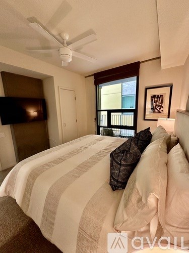 A bedroom with a bed, a ceiling fan, and a window.