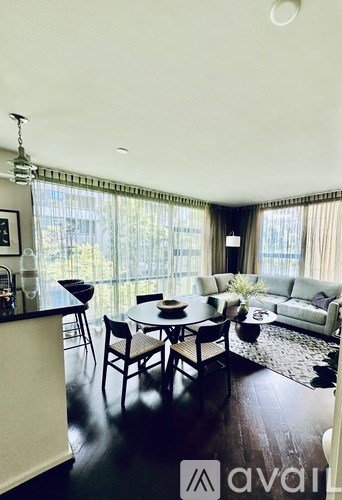 A dining room with a table set for four and a couch in the background.