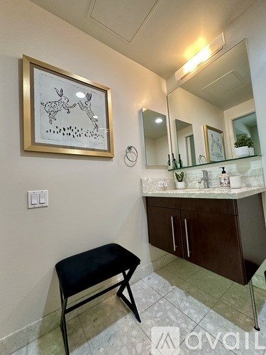 A bathroom with a black stool and a framed picture of a rabbit on the wall.