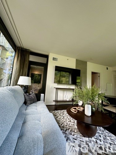 A living room with a grey couch and a coffee table with a plant on it.