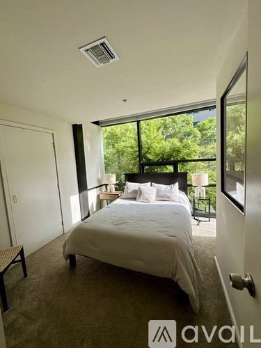 A bedroom with a large bed and a balcony overlooking trees.