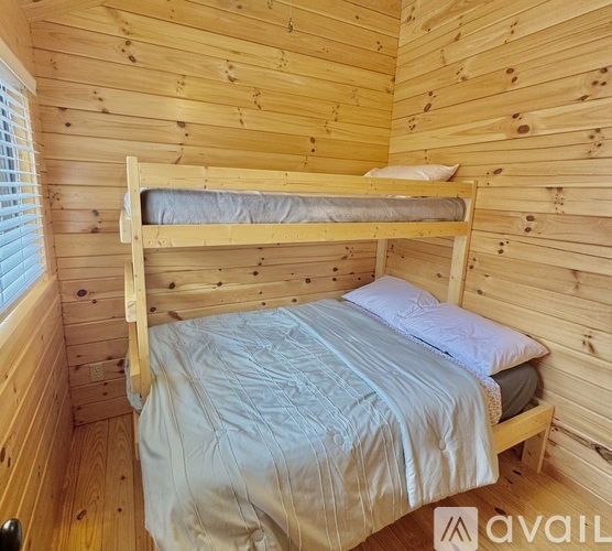 A wooden bunk bed with a blue comforter is in a room with wooden walls.