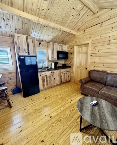 A wooden cabin with a couch, table, and a refrigerator.