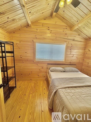 A bedroom with wooden walls and a bed with a white comforter.