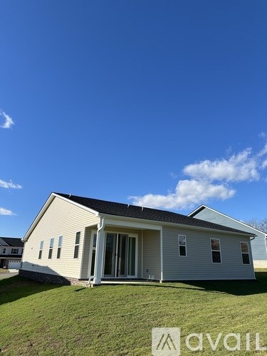 A house with a white exterior and a black roof is shown with a clear blue sky in the background.