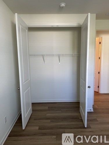 A white closet with a wooden floor and a white door.