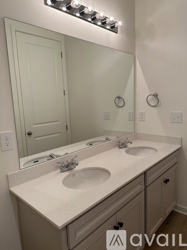 A bathroom with a double sink vanity and a mirror above it.