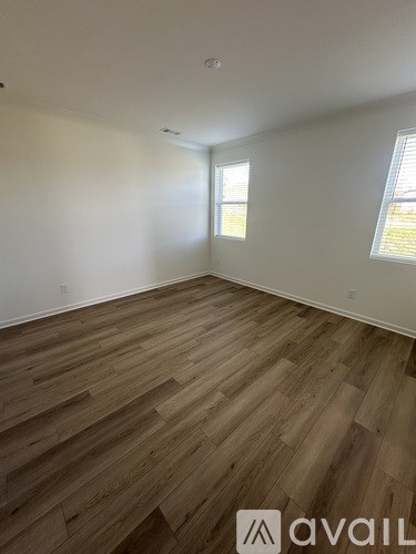 A room with wooden flooring and a window on the right side.