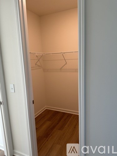 A small, empty closet with a white door and a wooden floor.