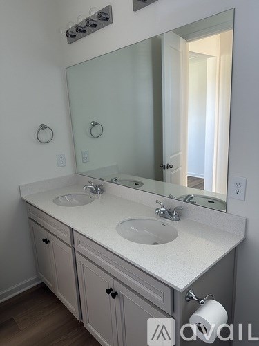 A bathroom with a white counter top and a large mirror.