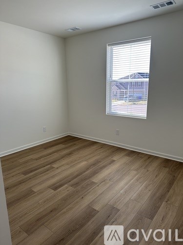 A room with wooden flooring and a window with blinds.