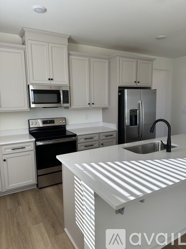 A kitchen with white cabinets and a stainless steel refrigerator.