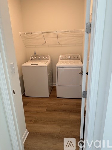 A laundry room with two washing machines and a clothes rack.