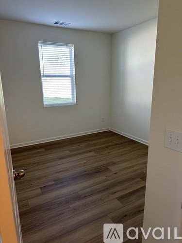 A room with wooden flooring and a window with blinds.
