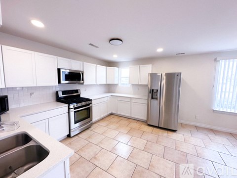 A kitchen with white cabinets and a tile floor.