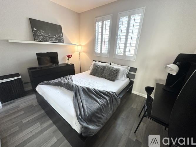 A bedroom with a bed, a television, and a lamp.