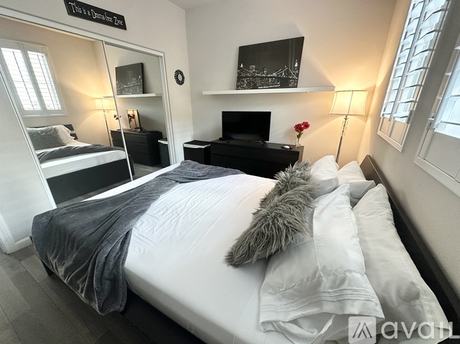 A bedroom with a bed, a TV, and a lamp.