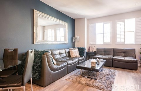 A living room with a brown leather couch and a glass coffee table.