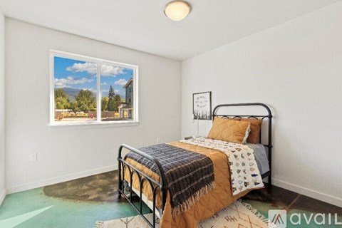 A bedroom with a large bed and a window showing a view of the outdoors.