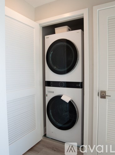 A white washing machine is in a cabinet in a room.