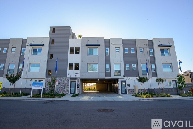 A modern apartment building with a stone entrance and multiple flags.