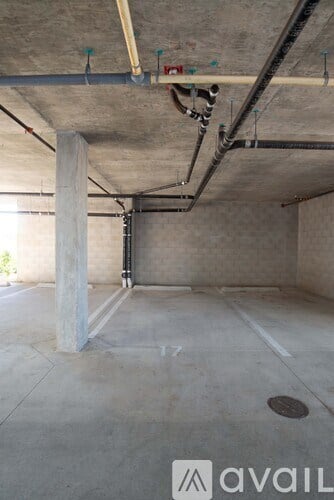 A large empty room with a concrete floor and exposed pipes on the ceiling.