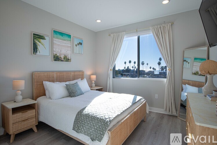 A bedroom with a large bed and a view of palm trees outside the window.