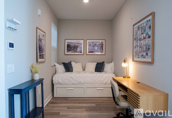 A bedroom with a bed, desk, and pictures on the wall.