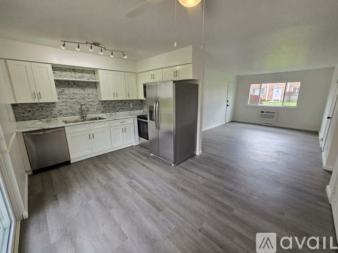 A kitchen with a refrigerator, sink, and cabinets.