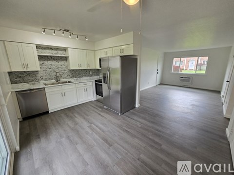 A kitchen with a refrigerator, sink, and cabinets.