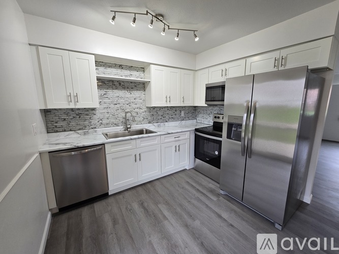 A kitchen with a refrigerator, sink, and cabinets.