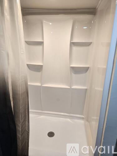 A white shower stall with a drain in the middle.