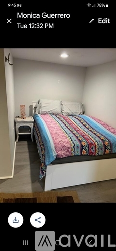 A bedroom with a bed covered in a multicolored blanket.
