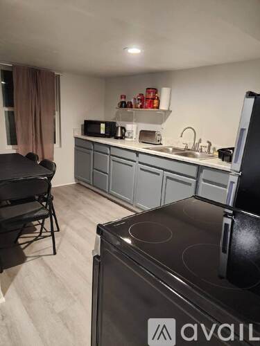 A kitchen with a black stove top oven and grey cabinets.