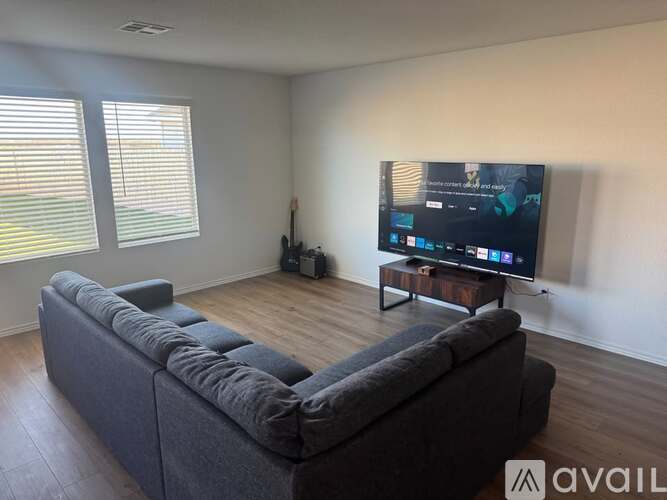 A modern living room with a grey sofa and a flat screen TV mounted on the wall.