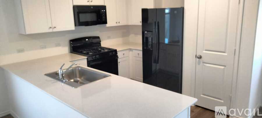 A kitchen with a black fridge and white countertops.