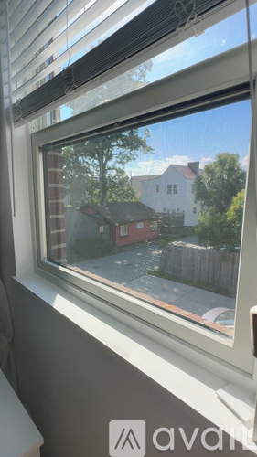A bedroom with a bed, a nightstand with a lamp, and a window with curtains.