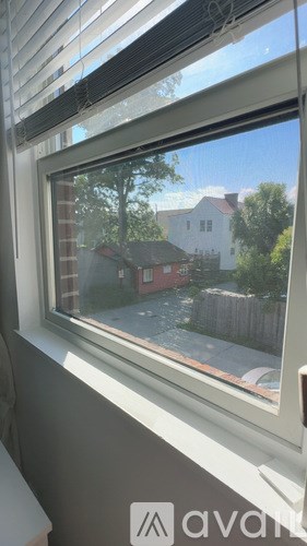 A bedroom with a bed, a nightstand with a lamp, and a window with curtains.