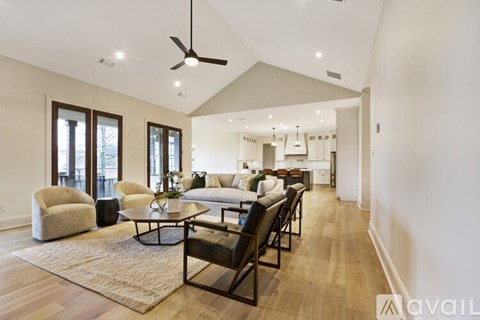 A spacious living room with a black ceiling fan and a large rug on the floor.