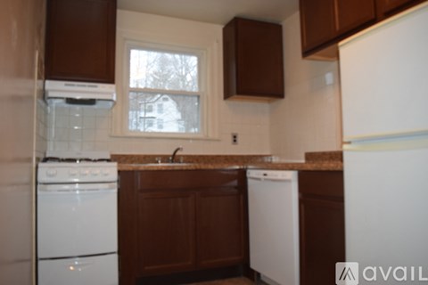 A kitchen with brown cabinets and a white dishwasher.