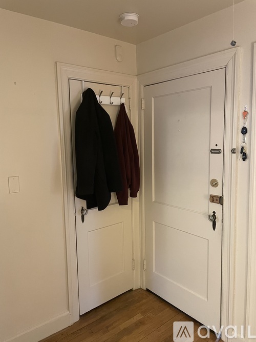 A white door with a coat hanging on it.