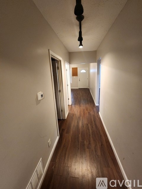 A long hallway with wood floors and white walls.