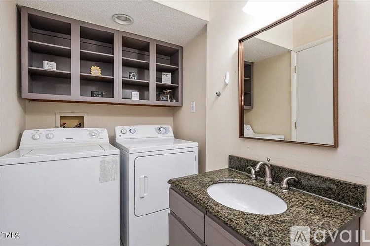 A laundry room with a washer and dryer, a sink, and a mirror.