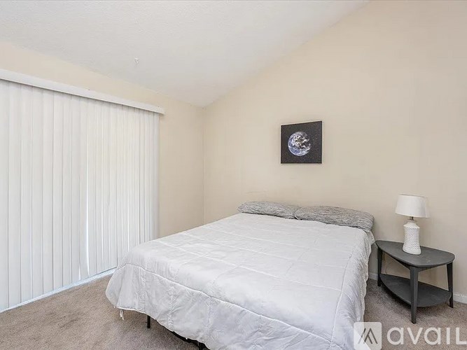 A bedroom with a bed, nightstand, and a picture of the moon on the wall.