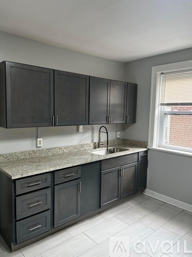 A kitchen with black cabinets and a granite countertop.