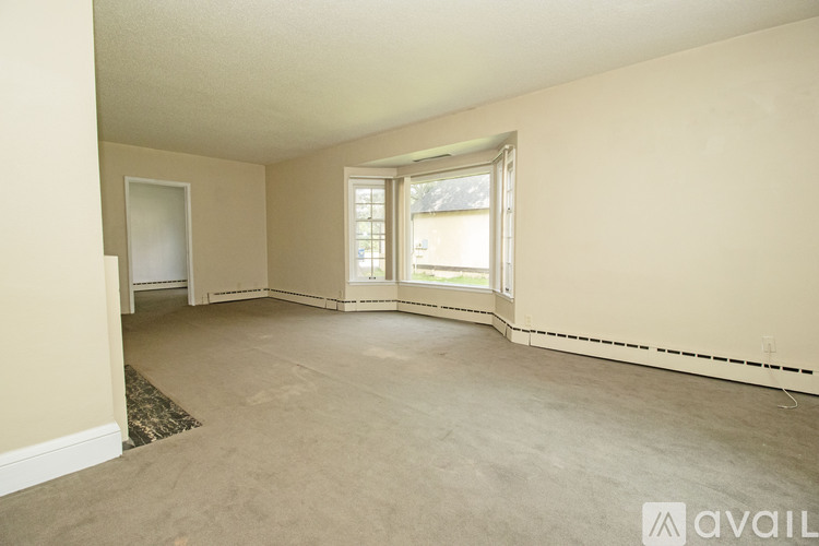 A spacious room with a window and a door on the left side.